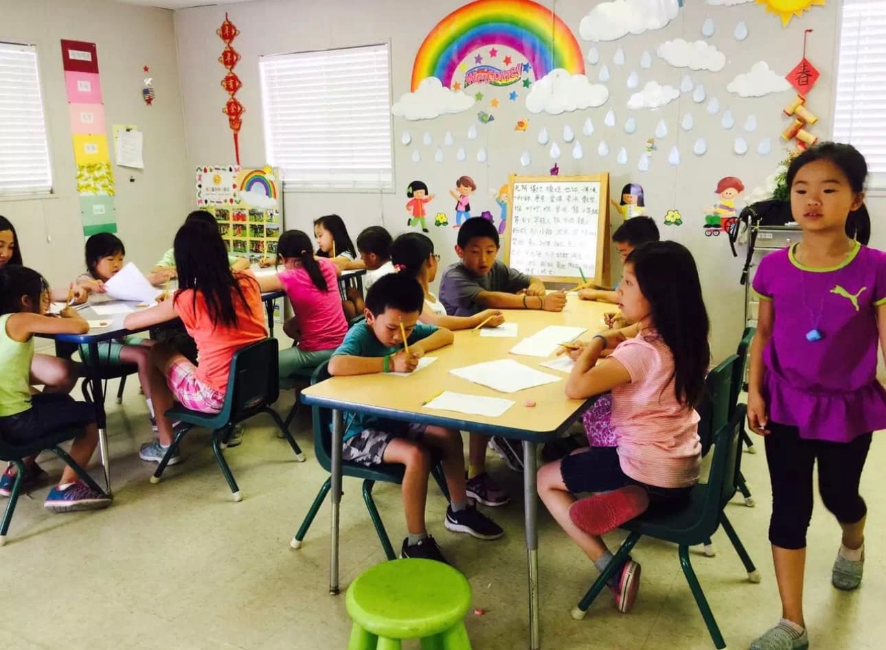 Students practice Chinese writing in a decorated classroom.