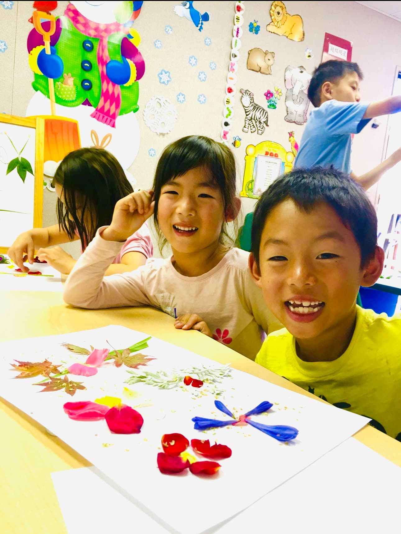 孩子们用花瓣和绿叶创作手工贴画。